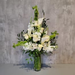 Tall white floral arrangement in a clear glass vase