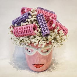 Pink face vase with white baby's breath and pink and purple curlers