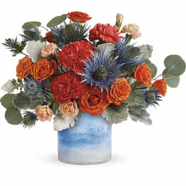 Orange and red flowers arranged in a blue ceramic vase