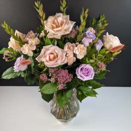 Bouquet of blush and lavender roses in a clear glass vase