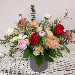 Mixed bouquet of pink, red, and white flowers in a gray vase