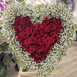 Heart-shaped red rose arrangement surrounded by white baby's breath