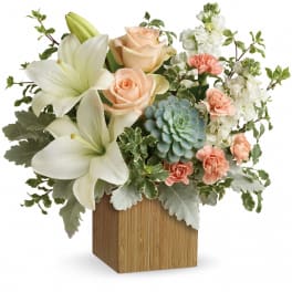 White lilies and peach roses arranged in a wooden cube vase