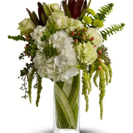 White and green floral arrangement in a tall glass vase