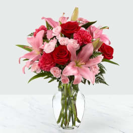 Pink lilies and red roses arranged in a clear glass vase