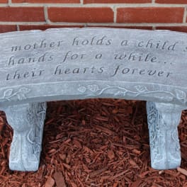 Stone bench with an engraved quote in front of a brick wall