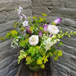 Mixed bouquet with purple calla lilies, white blooms, and green flowers in a glass vase