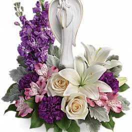 Purple and white floral arrangement with an angel figurine