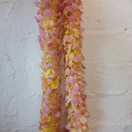 Two long pink and peach flower garlands hanging against a wall