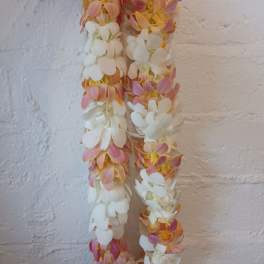 Two hanging garlands of white and pink flowers against a textured wall