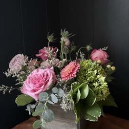 Pink roses and mixed blooms arranged in a wooden box