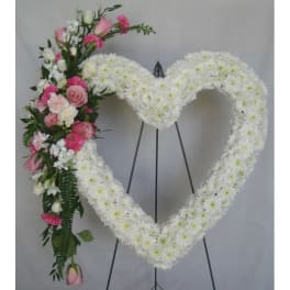 Heart-shaped white floral funeral wreath with pink roses and carnations