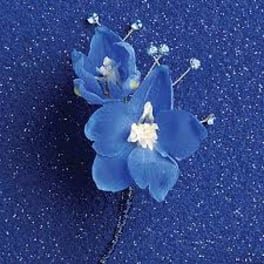 Blue orchid corsage with small white filler flowers on a sparkly blue background