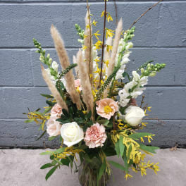 Tall bouquet of white and blush flowers in a glass vase