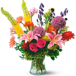 Mixed bouquet of pink, purple, orange, and yellow flowers in a glass vase