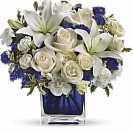 White roses and lilies in a blue glass vase
