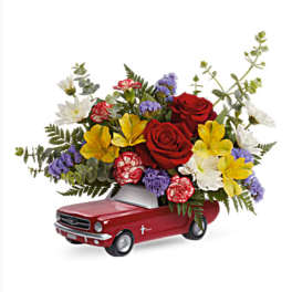 Flower arrangement in a red toy car with roses and mixed blooms