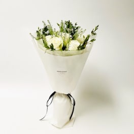 White rose bouquet wrapped in paper with a black ribbon
