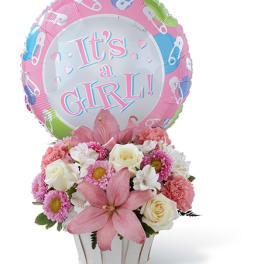 Pink and white flower arrangement with a "It's a Girl!" balloon