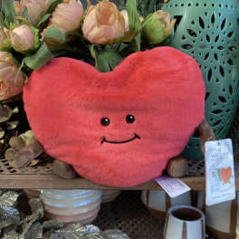 Heart-shaped plush toy in front of peach flowers and a teal lantern