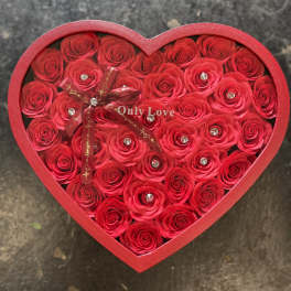 Heart-shaped box filled with red roses and a ribbon bow