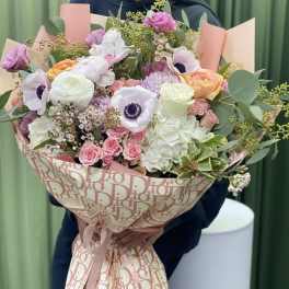 Large bouquet of pink, white, and peach flowers wrapped in patterned paper