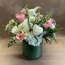 Pink and white roses arranged in a green cylindrical vase