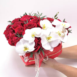 Red roses and white orchids arranged in a heart-shaped box