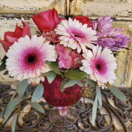 Pink and white gerbera daisies with roses in a red glass vase