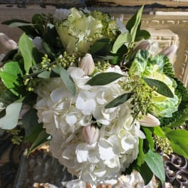 White hydrangea bouquet with pale pink tulips and green foliage