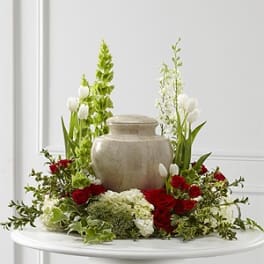 Red and white floral arrangement around a beige urn