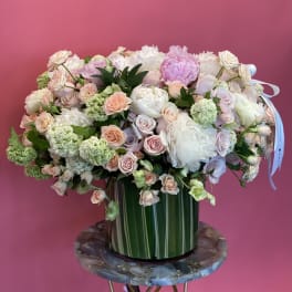 Large pastel bouquet in a striped green vase on a round table