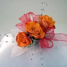 Orange rose corsage with pink ribbon and bead accents