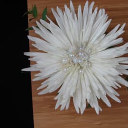 Large white flower with pearl center on a wooden surface
