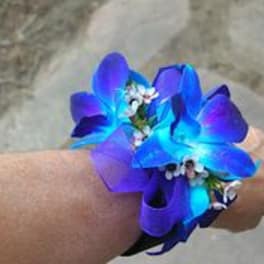 Blue and purple flower wrist corsage on a person's wrist