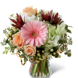 Bouquet of pink gerbera daisies and peach roses in a glass vase