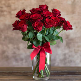 Bouquet of red roses in a clear glass vase with a red ribbon