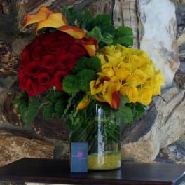 Bouquet of red and yellow roses with calla lilies in a glass vase