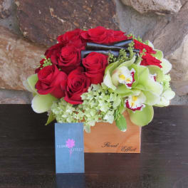Red roses and green orchids in a wooden box