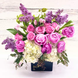 Pink roses and peonies with purple lilacs in a dark vase