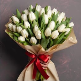 Bouquet of white tulips wrapped in beige paper with a red ribbon