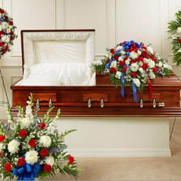 Casket surrounded by red, white, and blue funeral flower sprays