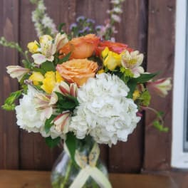 Bouquet of orange and yellow roses with white hydrangeas in a glass vase