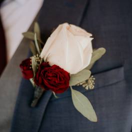 White rose boutonniere with red roses on a suit lapel