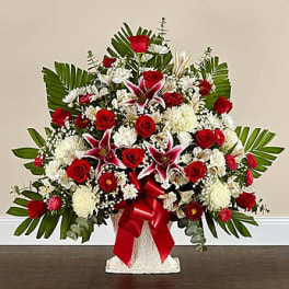 Large red and white floral arrangement in a white vase with a red ribbon