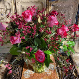 Pink roses in a clear glass vase with small pink filler flowers