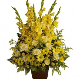 Yellow and white floral arrangement in a brown urn vase