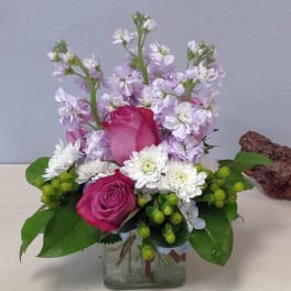 Pink roses and white flowers arranged in a clear glass vase