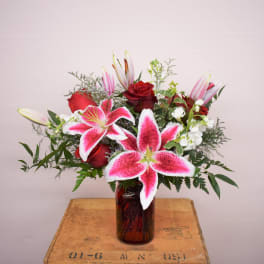 Bouquet of pink lilies and red roses in a glass vase