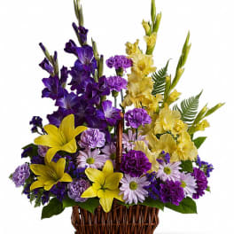 Purple and yellow floral arrangement in a wicker basket
